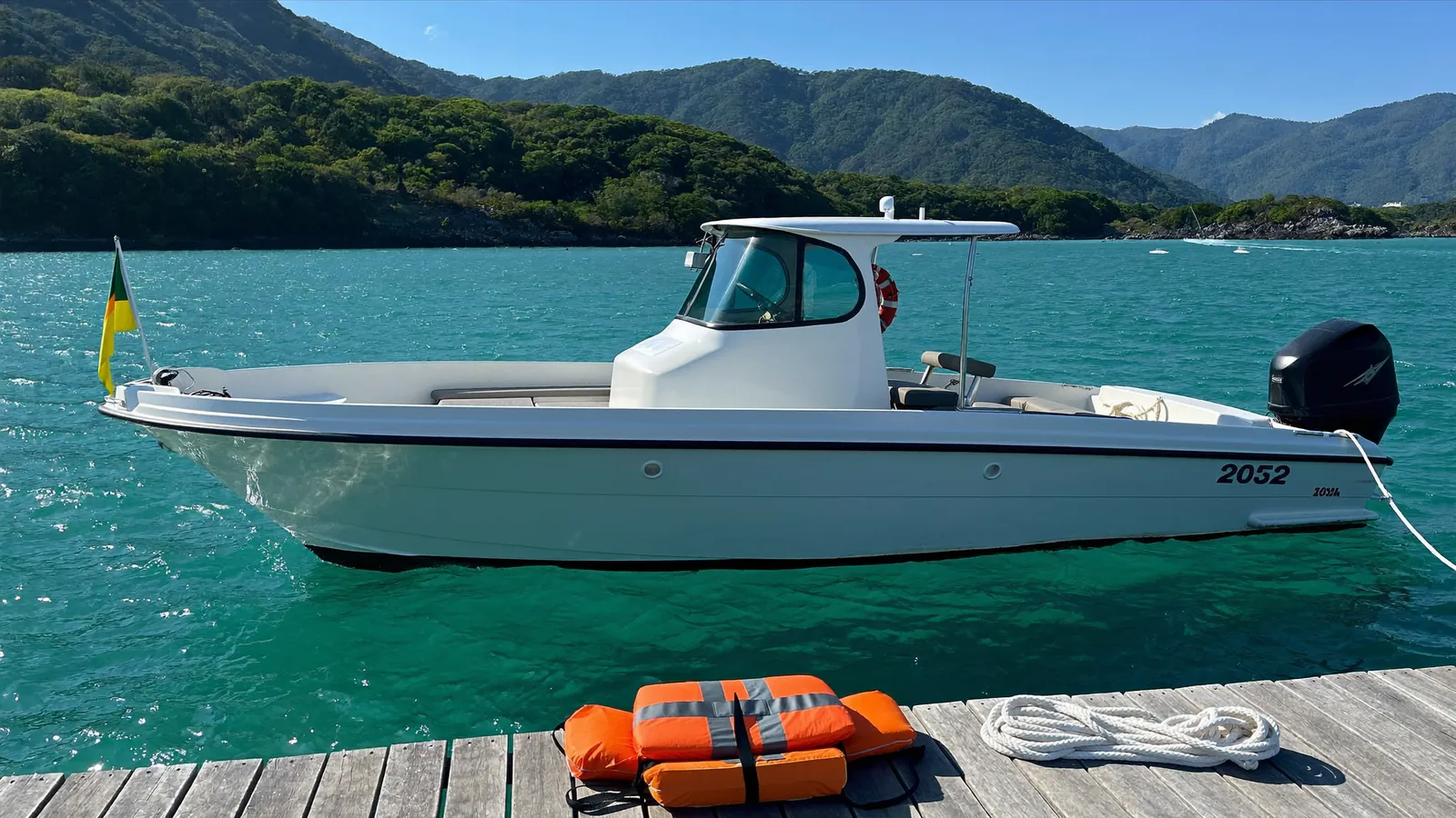 穏やかな湾に係留された小型ボートと、桟橋のライフジャケット